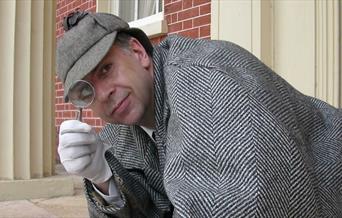 Actor dressed as Sherlock Holmes with Magnifying Glass