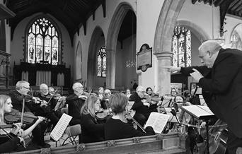 Black and white image of an orchestra playing in a church