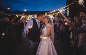 Bride and groom surrounded by guests with sparklers.