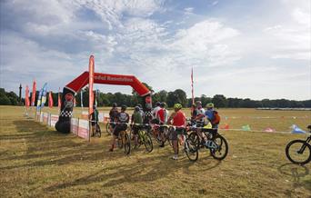 Cyclists at the finish line in Holkham Park on a summer's day.