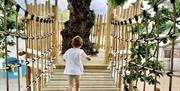 A young child running across a wooden tree top walkway.