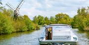 Cruiser in the Broads National Park passing a Norfolk windmill