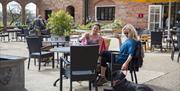 Visitors enjoying their coffee on the courtyard of the Squire's Pantry tea room on a sunny springtime day at Felbrigg Hall, Gardens and Estate, Norfol