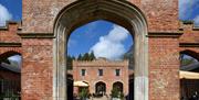 View through an archway to the courtyard with outside seating at Felbrigg Hall, Norfolk