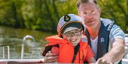 Dad and son at the wheel steering a Cruiser in the Broads National Park