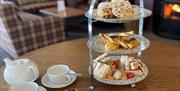 Afternnon tea stand with tea set. Sofas and log burner in the background.