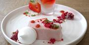 Red and pink strawberry parfait dessert on a white plate.