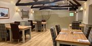 Dog friendly restaurant with tables and chairs, wooden floor and beamed ceiling.