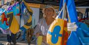 An extremely smiley stall holder, Rosie, of the Accidental Wonky Bag Company is looking directly at the camera surrounded by multi-coloured bags.