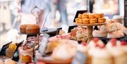 Hestia Patisserie is a maker luxury cakes and patisserie in Norfolk. The image shows their products on display at Holt Sunday Market. Products include