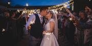 Bride and groom surrounded by guests with sparklers.