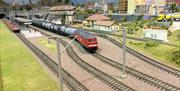 Model railway. European freight train hauling chemical wagons past the main city station.