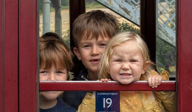 Children look through historic carriage window