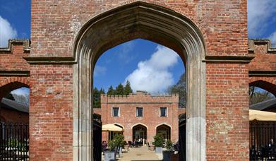 View through an archway to the courtyard with outside seating at Felbrigg Hall, Norfolk