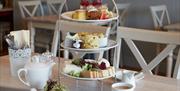 A selection of cakes, sandwiches and scones, displayed on an afternoon tea stand.