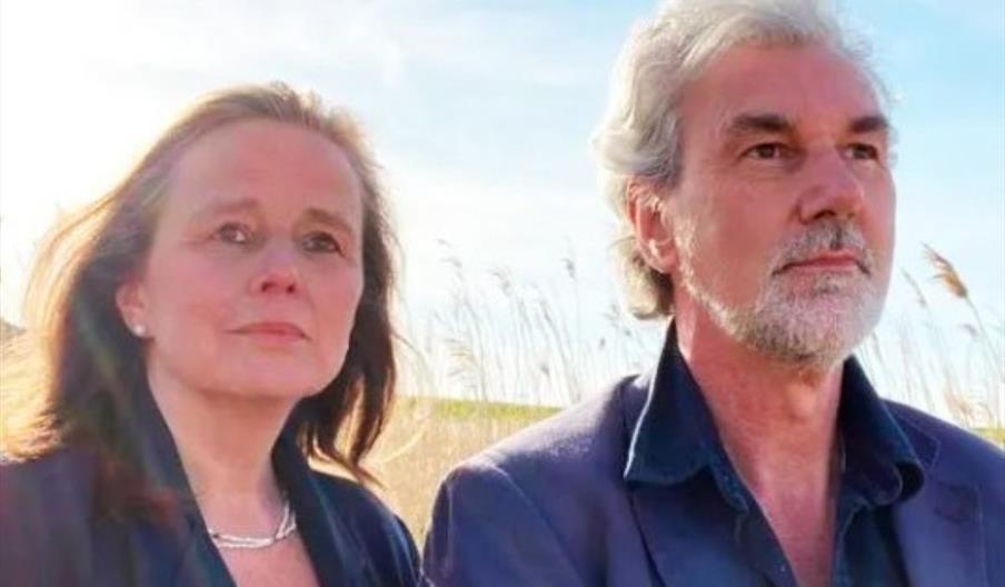 Headshot of a woman and a man standing outdoors looking just off the camera. Headshot of a woman and a man standing outdoors looking just off the camera.