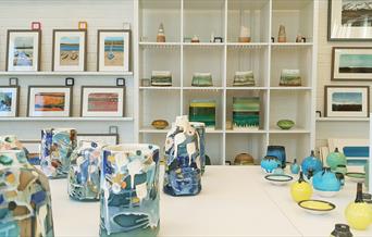 Image shows a view inside Gallery Plus, with ceramics and paintings displayed