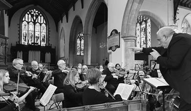 Black and white image of an orchestra playing in a church