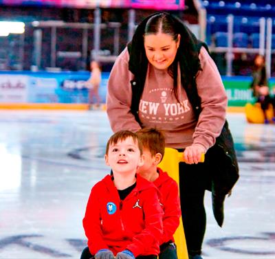 Photo of a mum and two young boys enjoying an ice-skating session, using ice equipment
