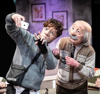 Photo of the stage show showing two puppets: one of a young boy, the other of an old man