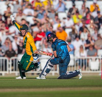 Photo of a cricket match showing two players mid-action