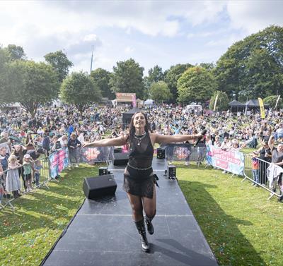 Image from a previous Ashfield Show showing a performer on stage with a large crowd behind them.