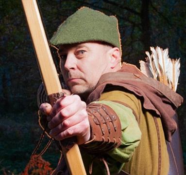 man dressed as robin hood doing archery