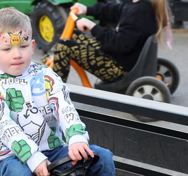 Photo of a young boy on a toy tractor