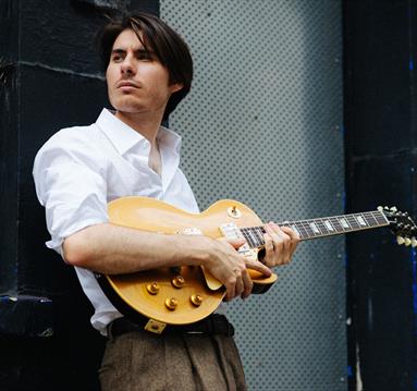 image of connor selby with his guitar
