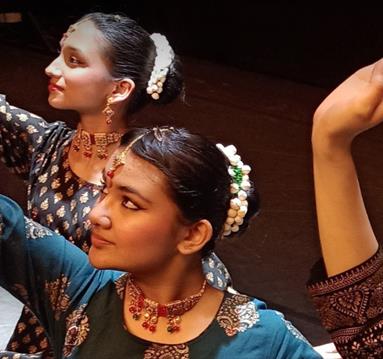 Four people dancing wearing black and gold sarees
