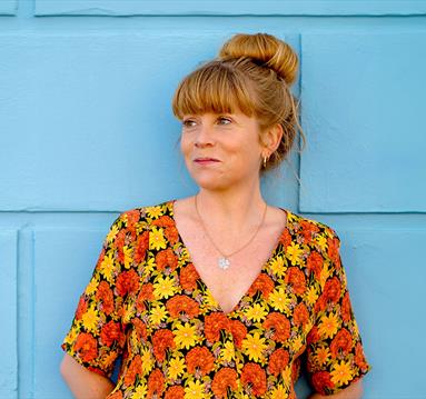 Sara Oschlag stood infront of a blue wall wearing a floral top