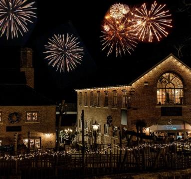 Fireworks behind the Engine Yard. The sky is dark and the fireworks stand out against the night sky.