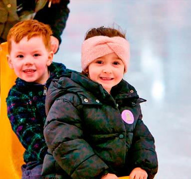 Photo of two young kids enjoying an ice-skating session using ice equipment