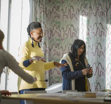 Three people standing round a table in front of a closed curtain