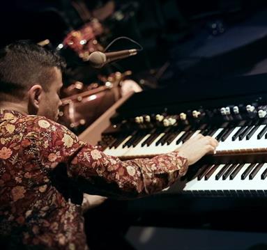 Photo of a jazz piano player from behind.