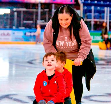 Photo of a mum and two young boys enjoying an ice-skating session, using ice equipment