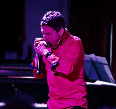 Photo of Adam Glasser playing the harmonica
