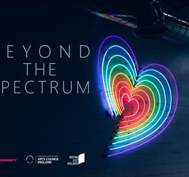 A neon heart with rainbow colours against a dark blue wall
