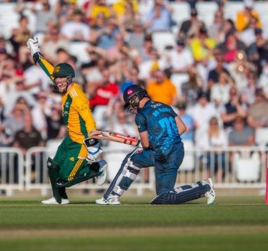 Photo of a cricket match showing two players mid-action