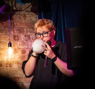 Photo o Cerys Bradley blowing a balloon up on stage