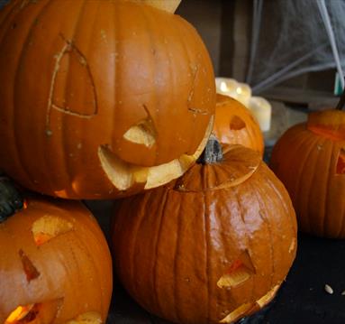 A small stack of pumpkins, carved with spooky faces.