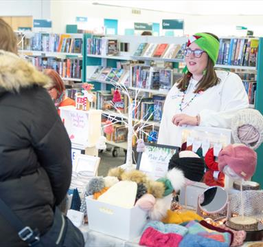 A person talking to a stallholder at a Christmas market
