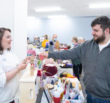 A market stallholder smiling as a shopper browses the stall