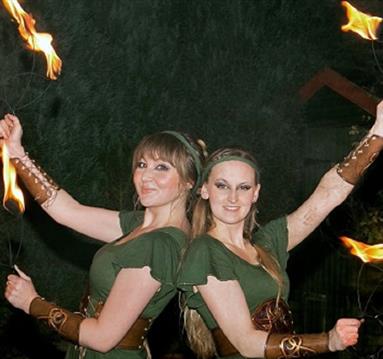Two women in Robin Hood costumes juggling with fire