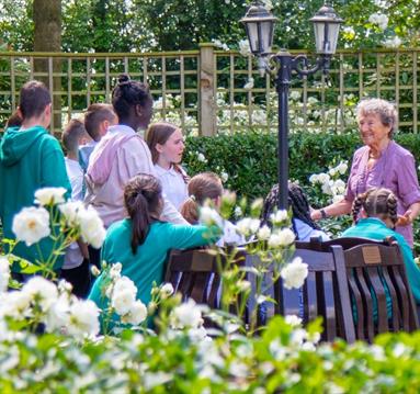 Photo of Holocaust Survivor Hedi Argent MBE with a group of children in the memorial gardens