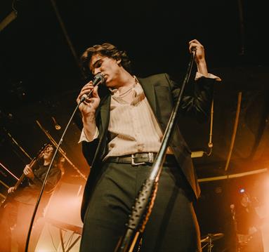 Photo of a singer with bright lights behind them