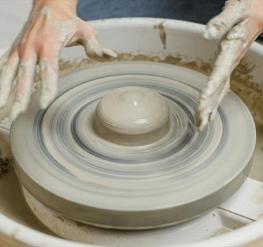Photo of a potter using a throwing wheel