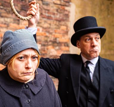 Two costumed actos recreating the scene of a woman at the gallows, with a noose about to be tied around her neck