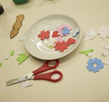 Photo of a crafts table with cut out bits of paper