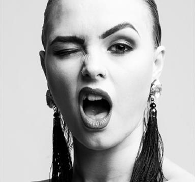The image shows a womans face in back and white with dangling earrings and lipstick on.